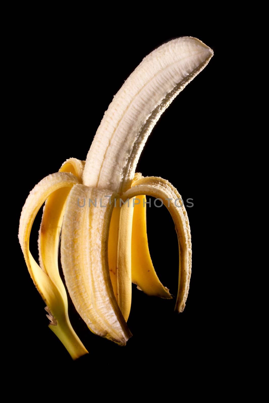 Close up view of peeled banana isolated on a black background.