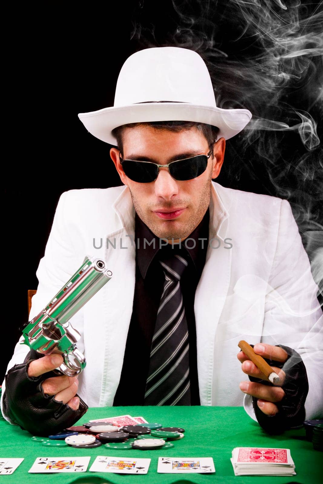 View of a gangster man playing some cards and poker, smoking a Cuban cigar.