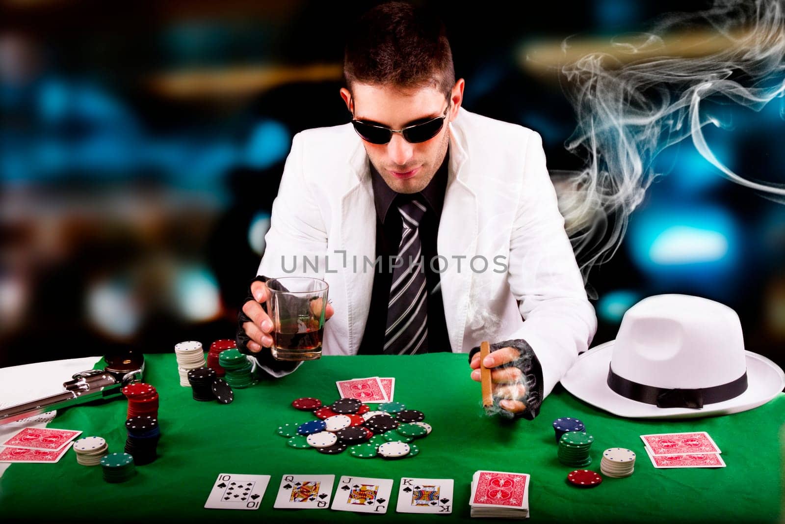 View of a gangster man playing some cards and poker, smoking a Cuban cigar.