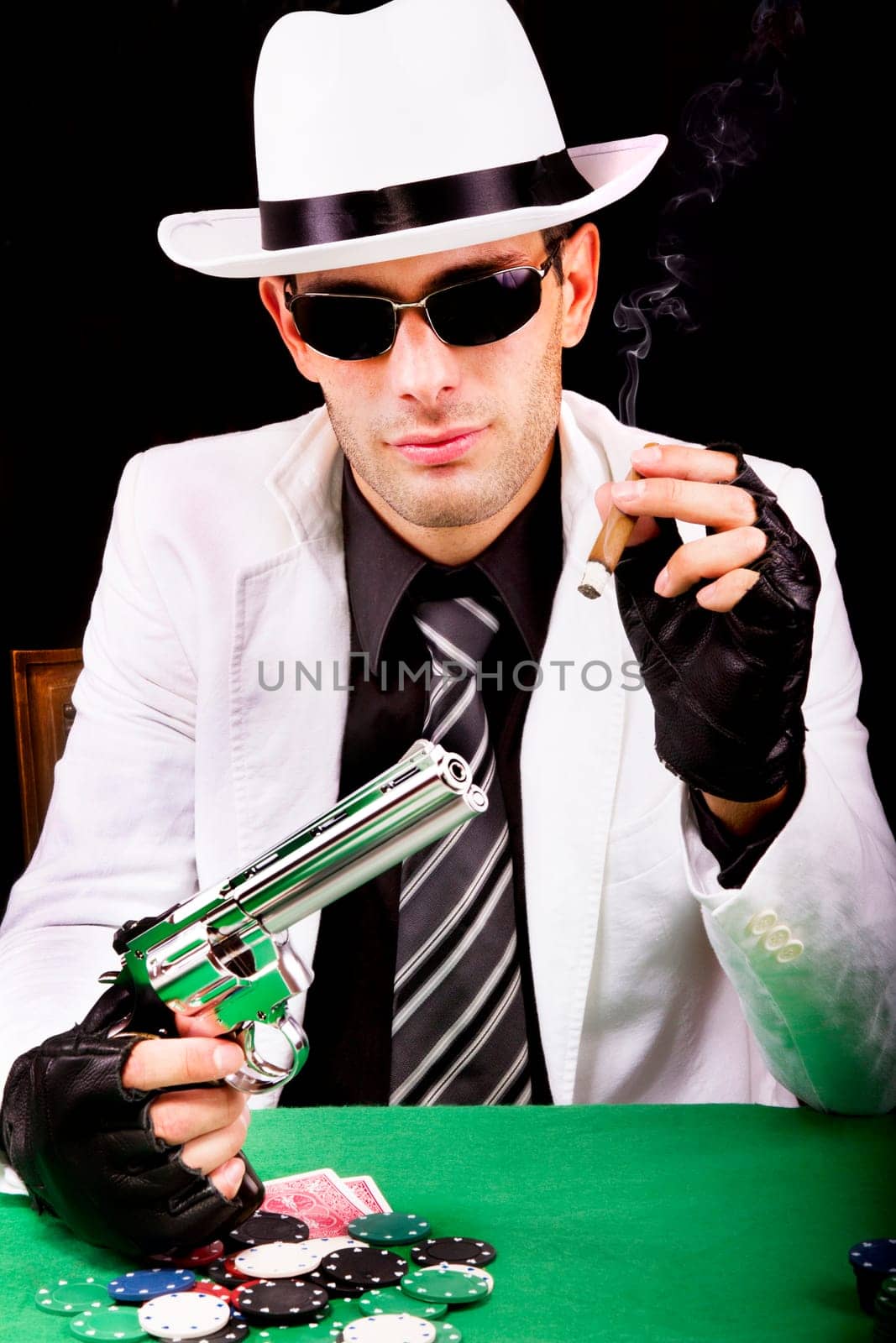 View of a gangster man playing some cards and poker, smoking a Cuban cigar.
