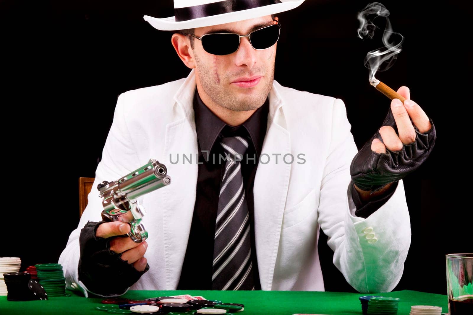 View of a gangster man playing some cards and poker, smoking a Cuban cigar.