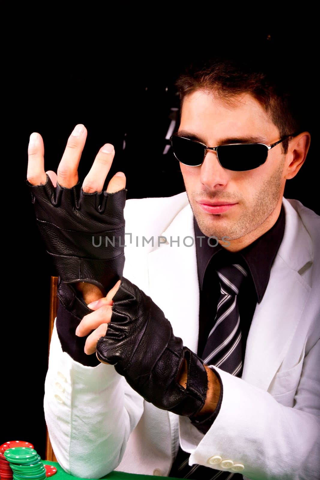 View of a gangster man playing some cards and poker, adjusting the gloves.