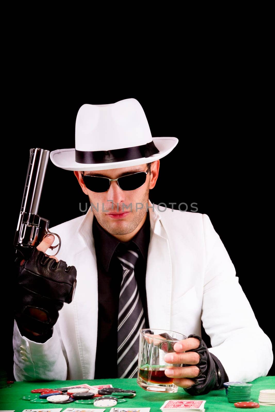 View of a gangster man playing some cards and poker, holding a gun.