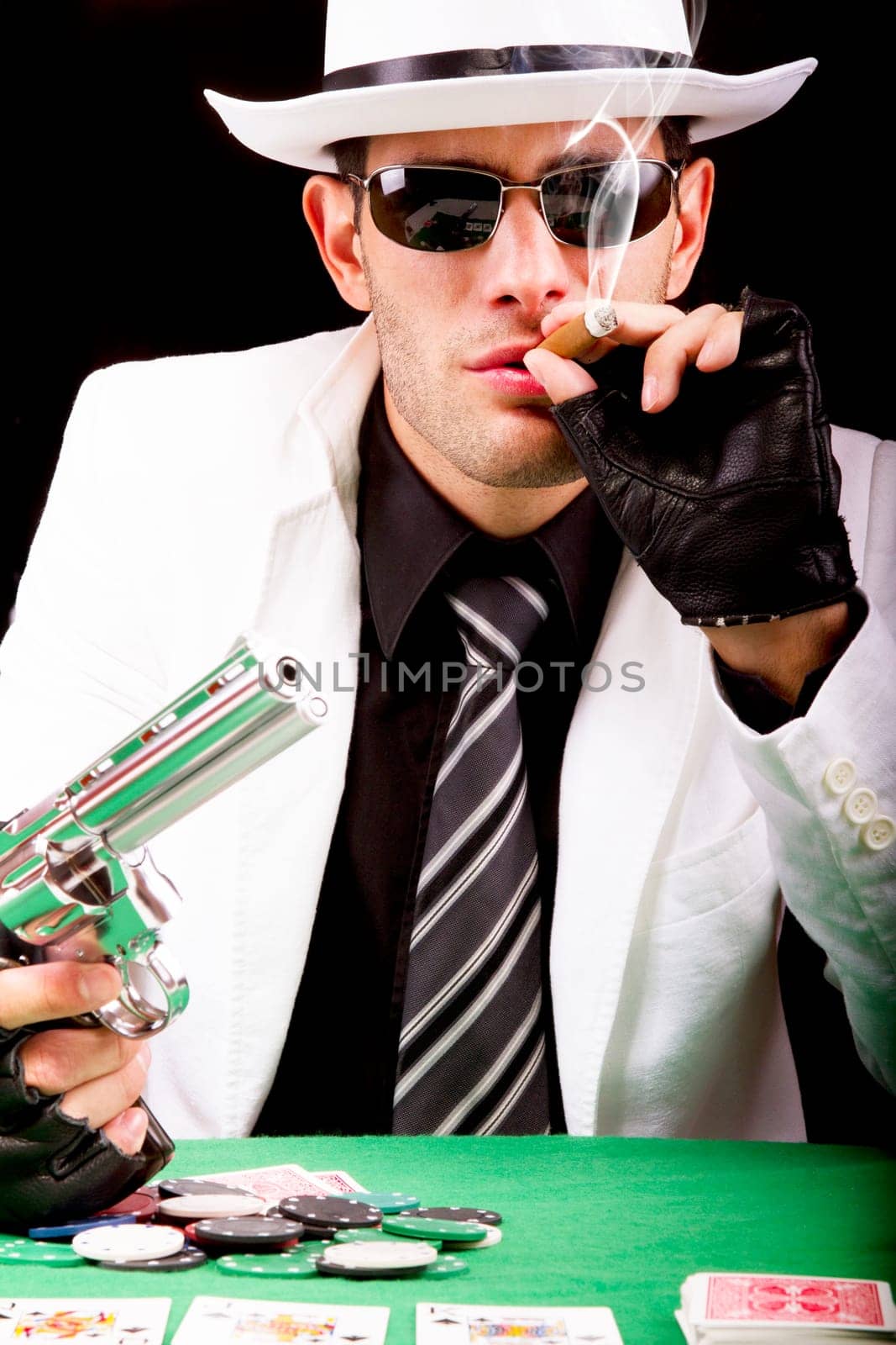 View of a gangster man playing some cards and poker, smoking a Cuban cigar.