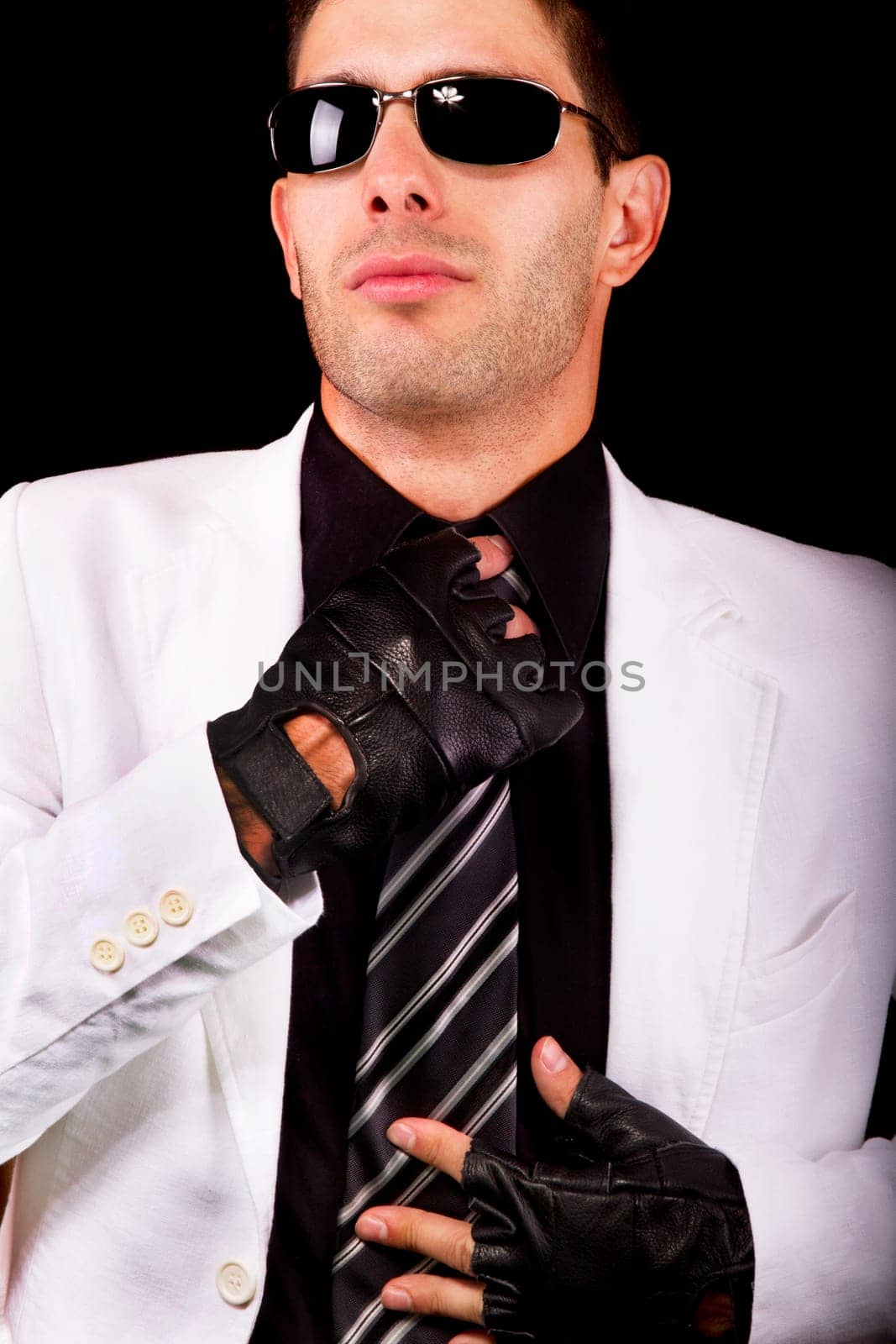 View of a white suit man with gloves, adjusting a tie.
