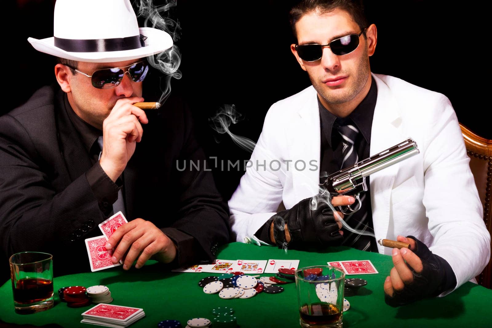 View of two gangster males playing some poker and smoking Cuban cigars.