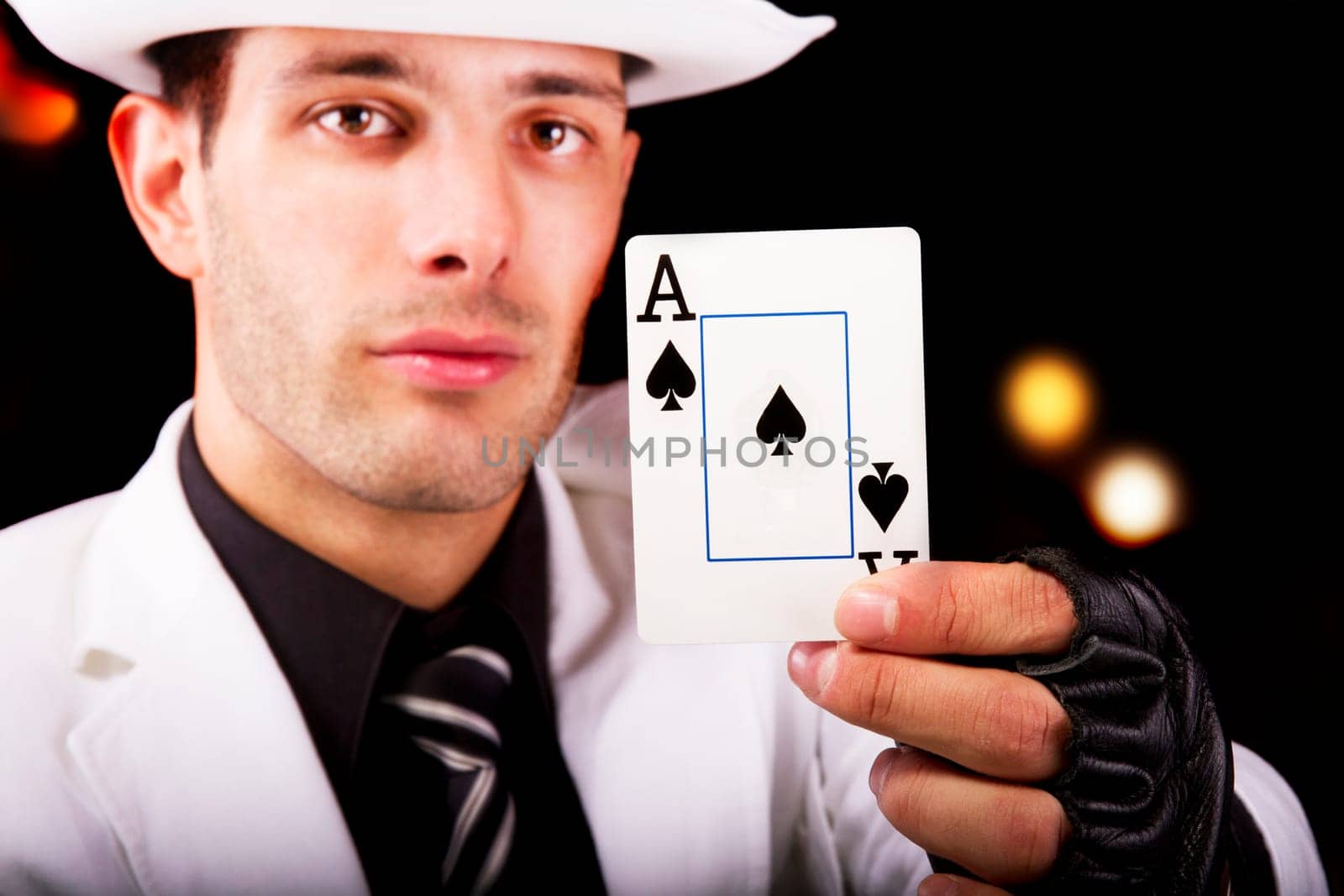 View of a white suit man with hat, holding an ace card.