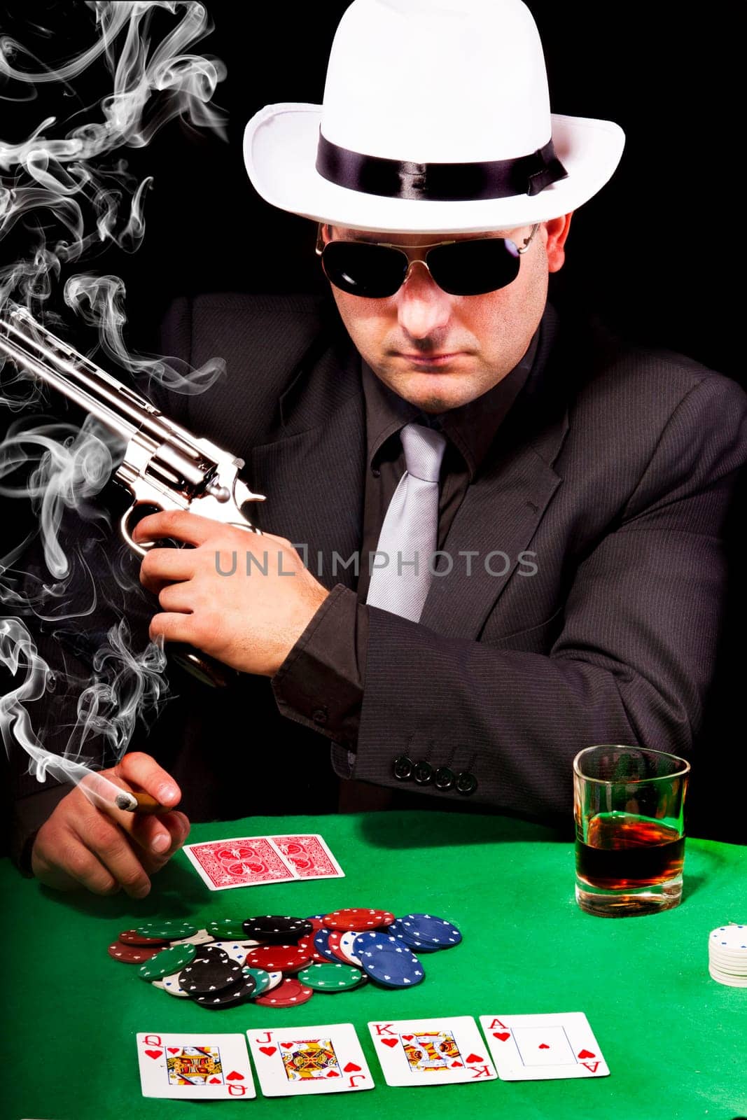View of a gangster man playing some cards and poker, smoking a Cuban cigar.