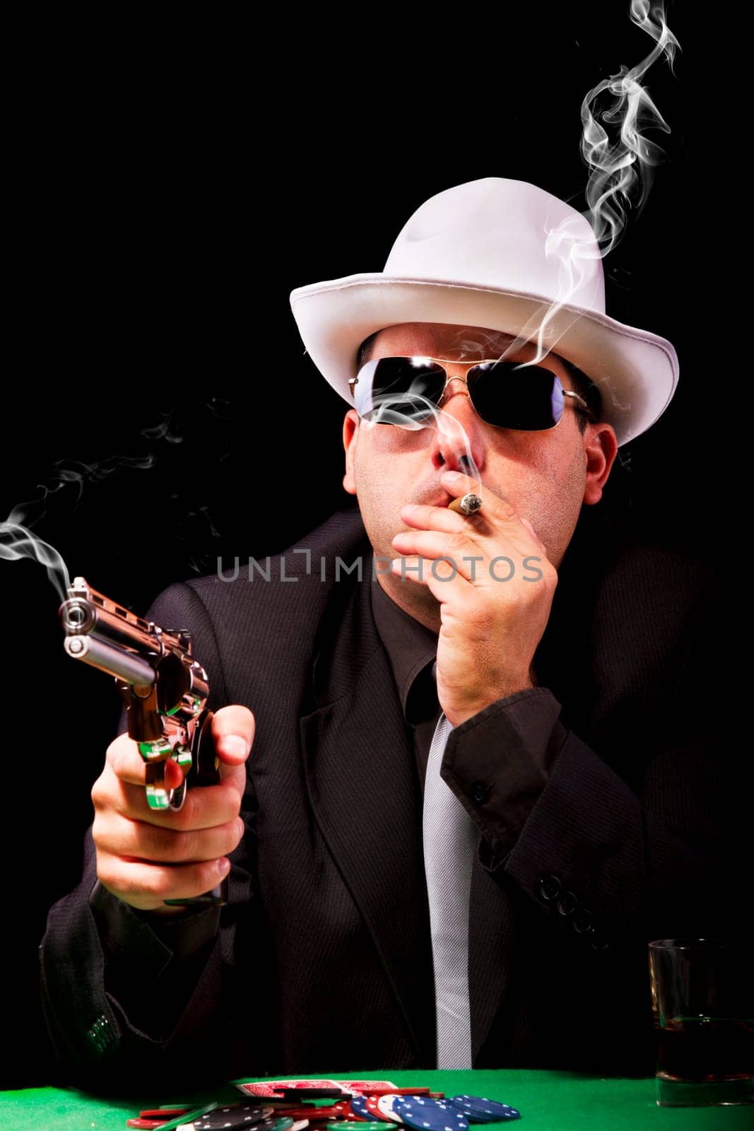 View of a gangster man playing some cards and poker, smoking a Cuban cigar.