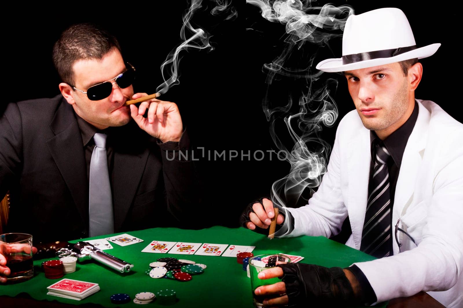 View of two gangster males playing some poker and smoking Cuban cigars.