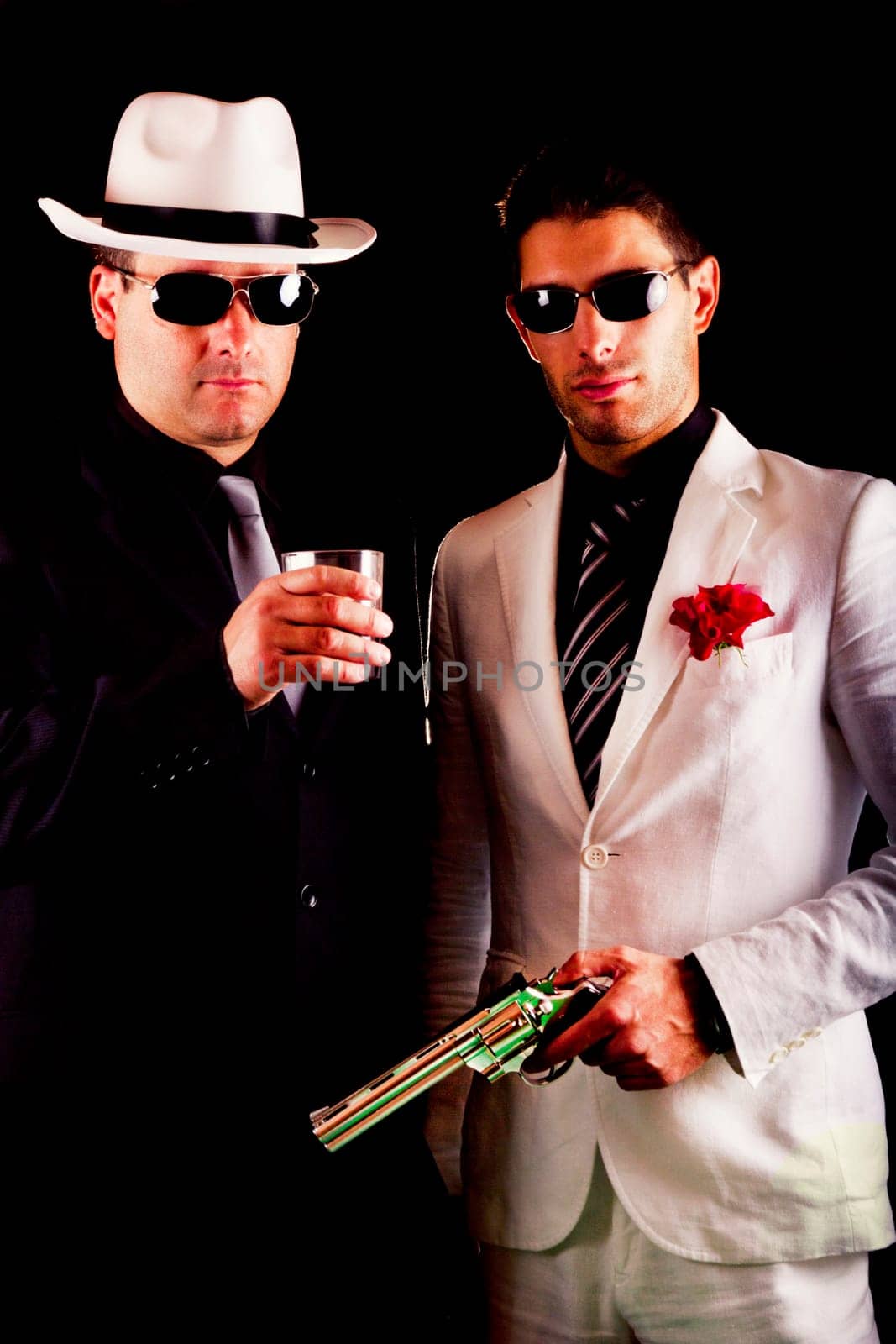 View of two gangster males holding a gun on a black background.