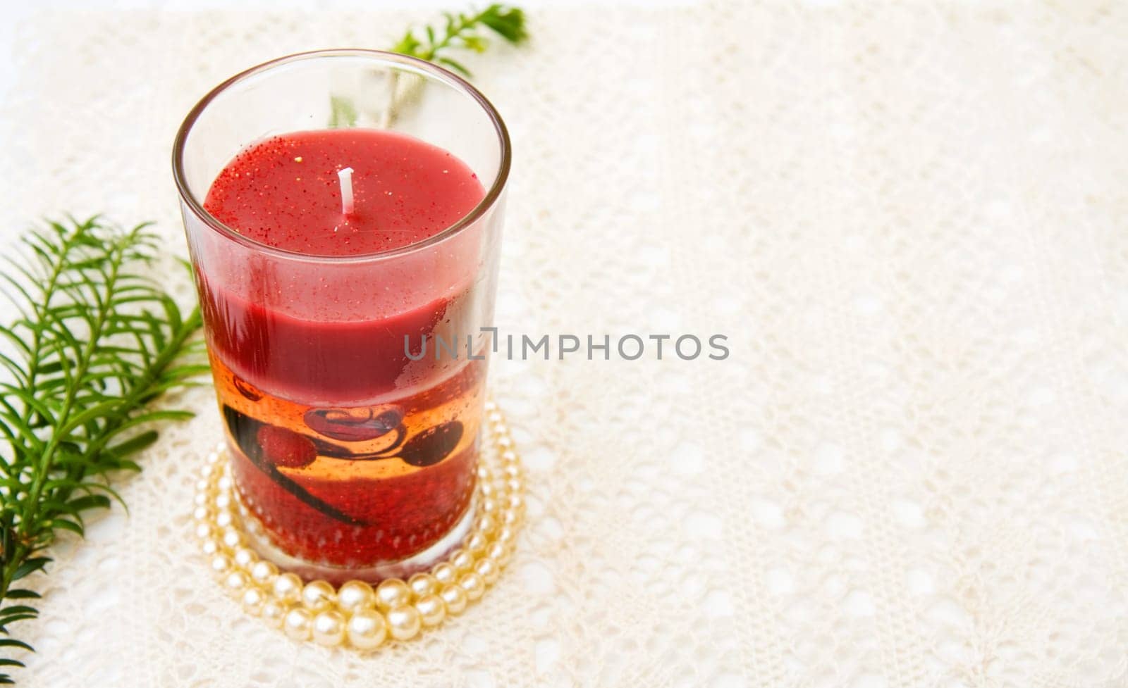 Celebrating Christmas with festive red candle on vintage, handmade lace. Room for your text.