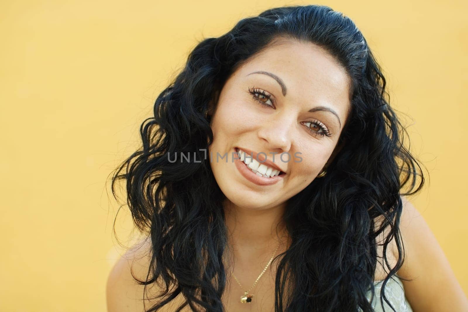 portrait of caucasian college student smiling and looking at camera with yellow wall in background. Selective focus, copy space