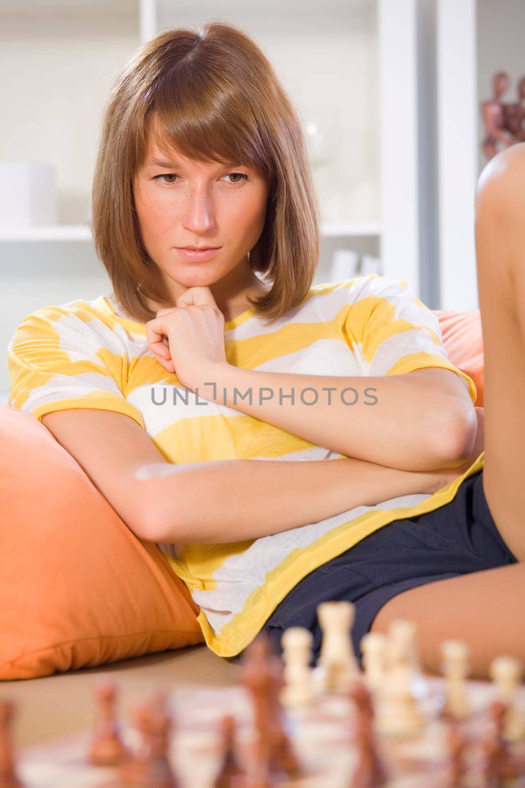 woman playing chess game while sitting on sofa