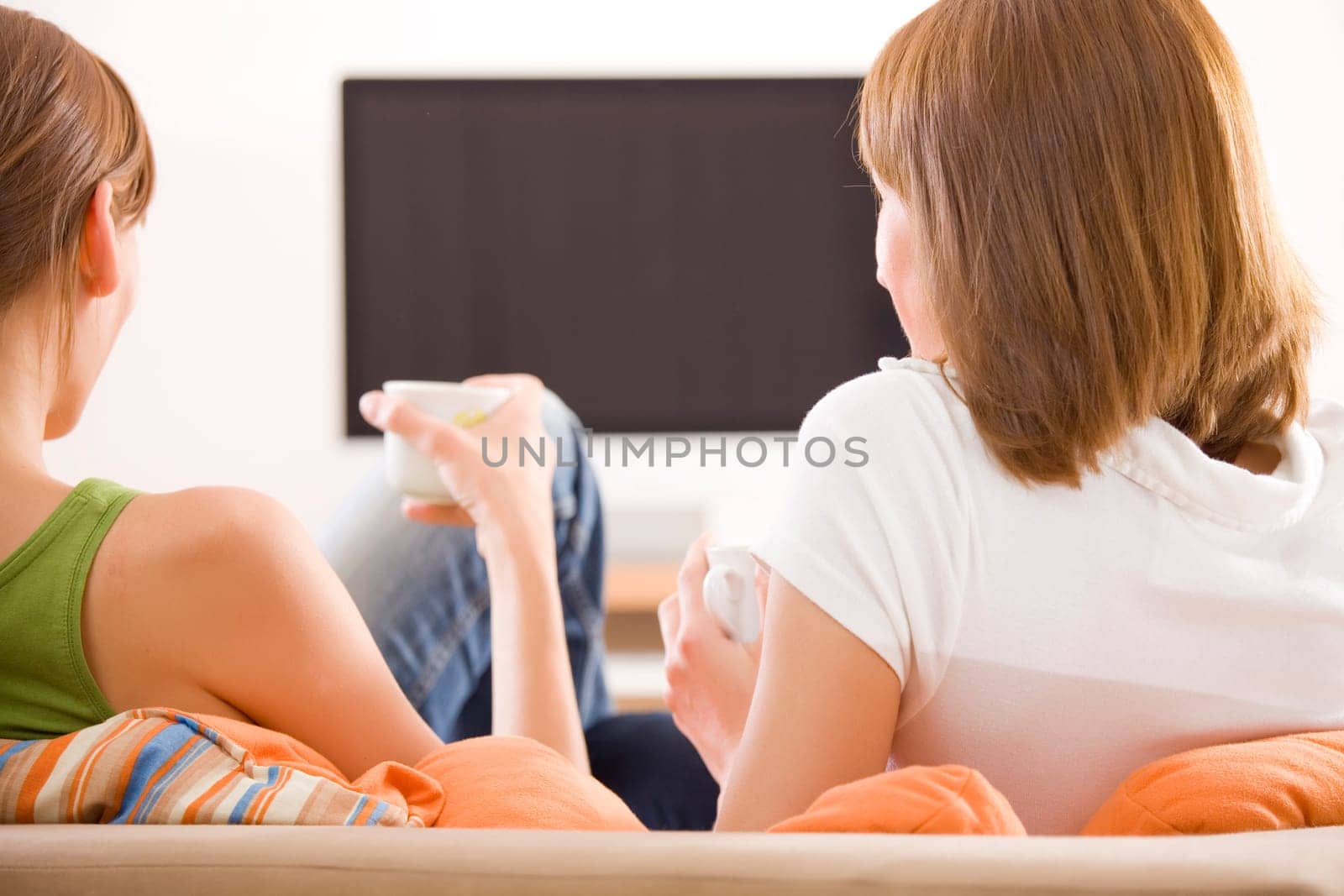 two women sitting in front of monitor watching television