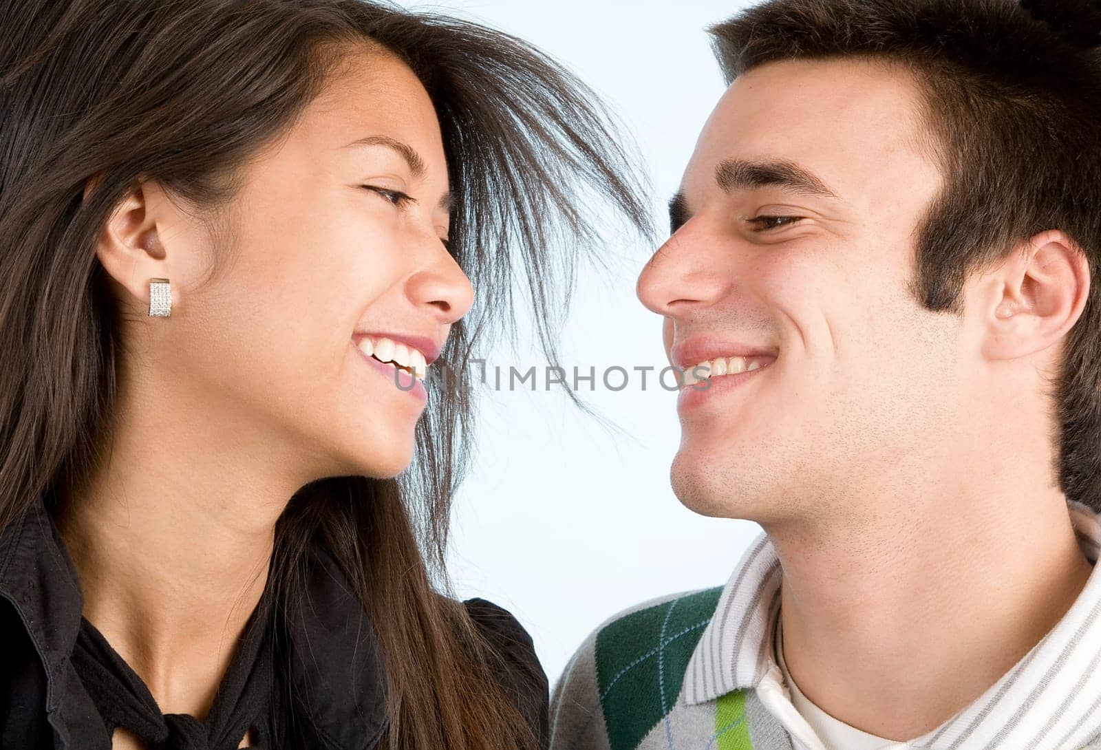 A young couple are laughing while looking at each other.