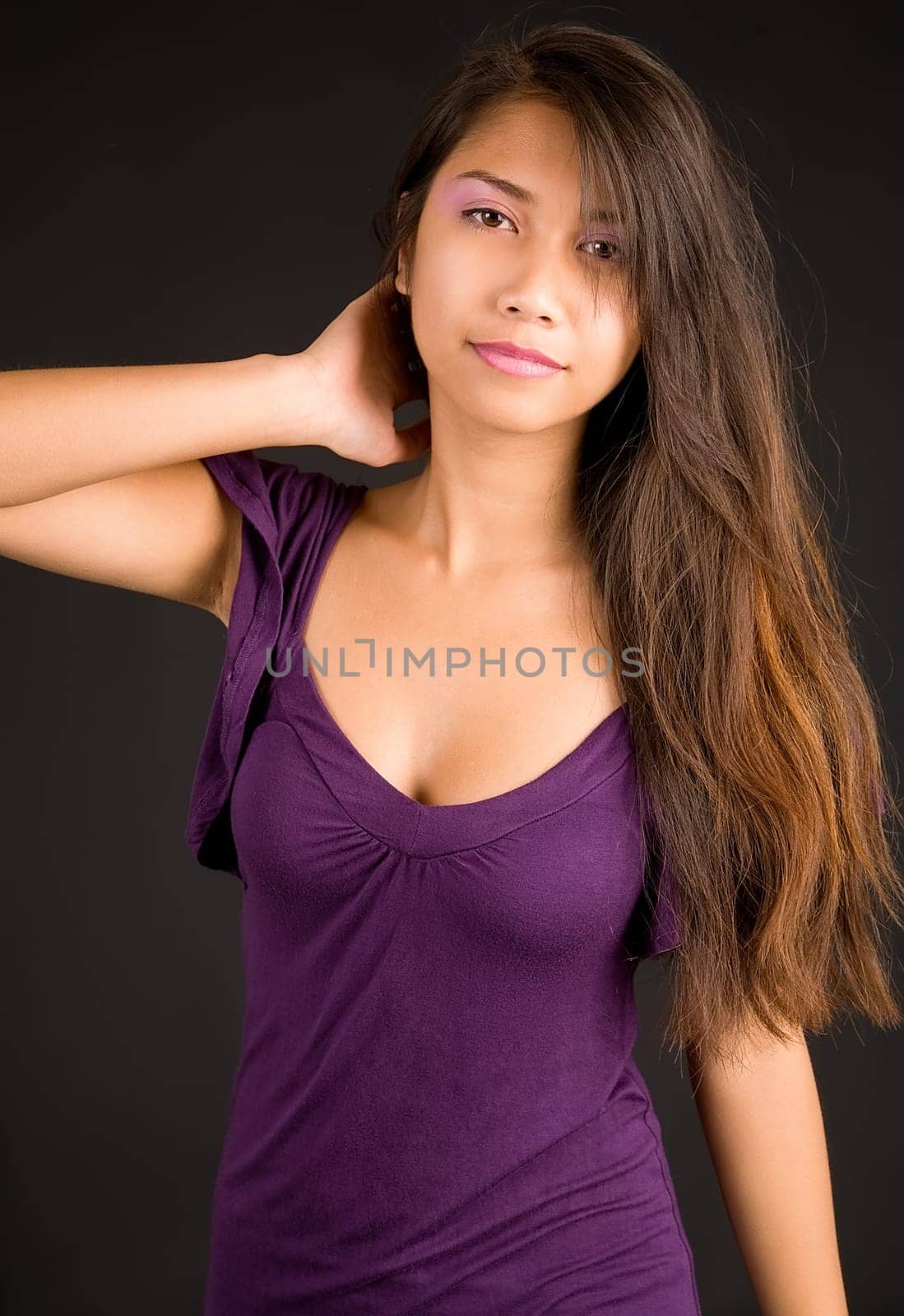 A beautiful young lady in a purple dress is looking at the camera.
