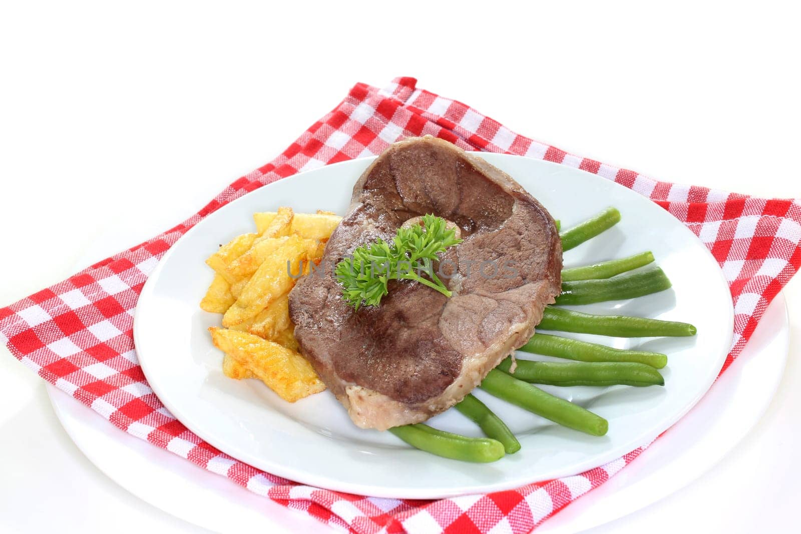 a slice of leg of lamb with green beans and fries