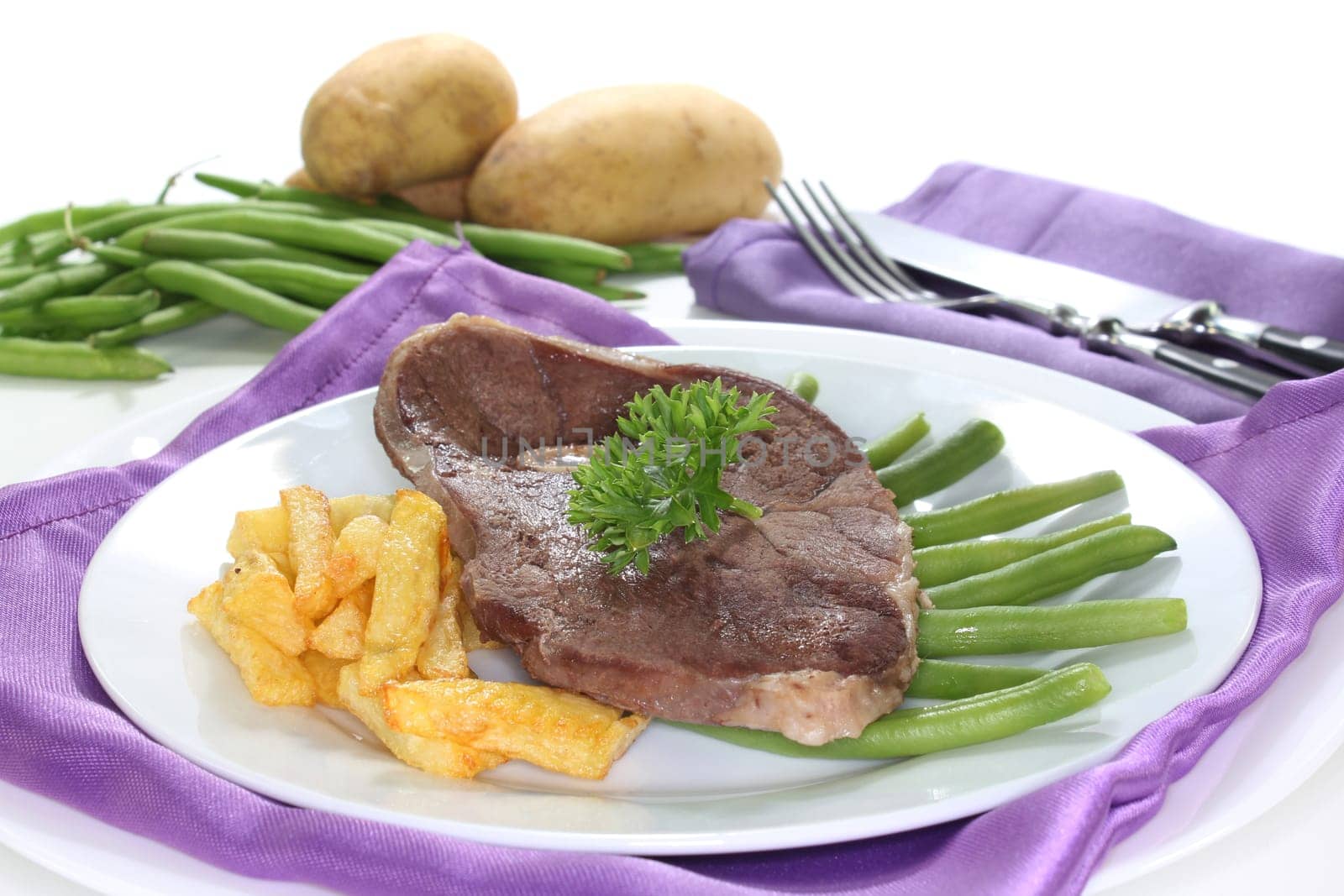 a slice of leg of lamb with green beans and fries