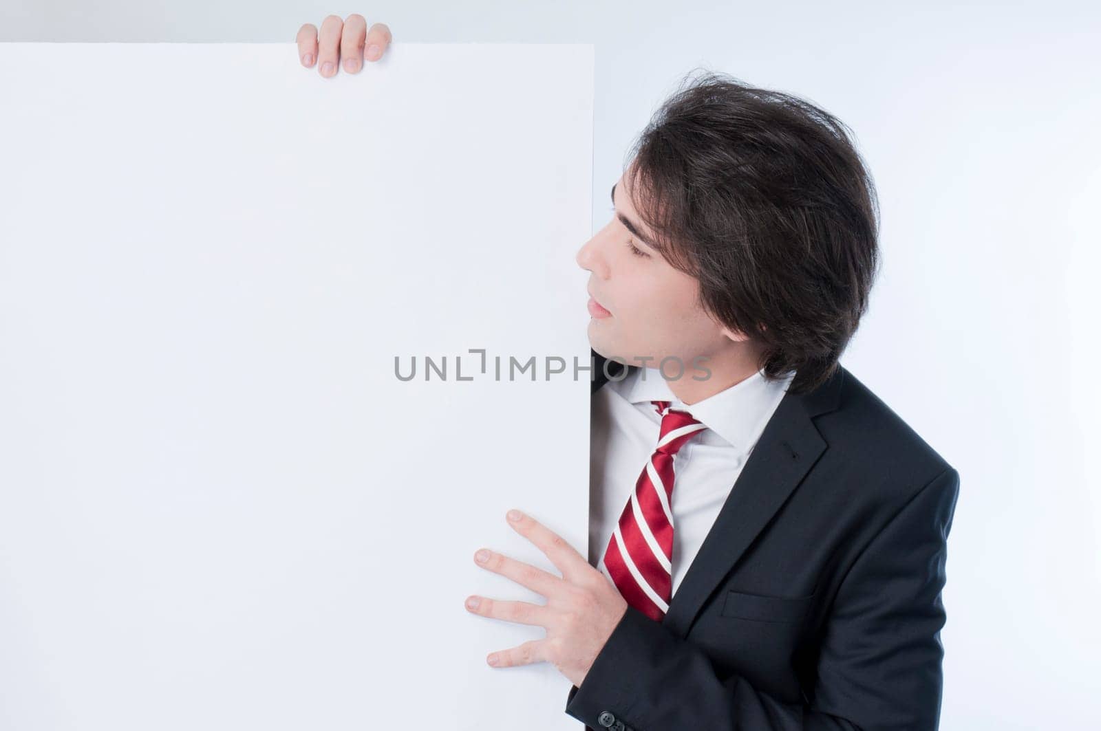 Young man appears from behind a white panel