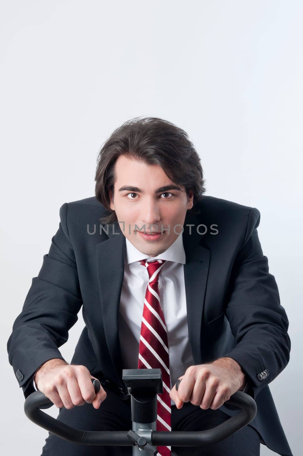 Young businessman riding a fitness bicycle isolated on white background