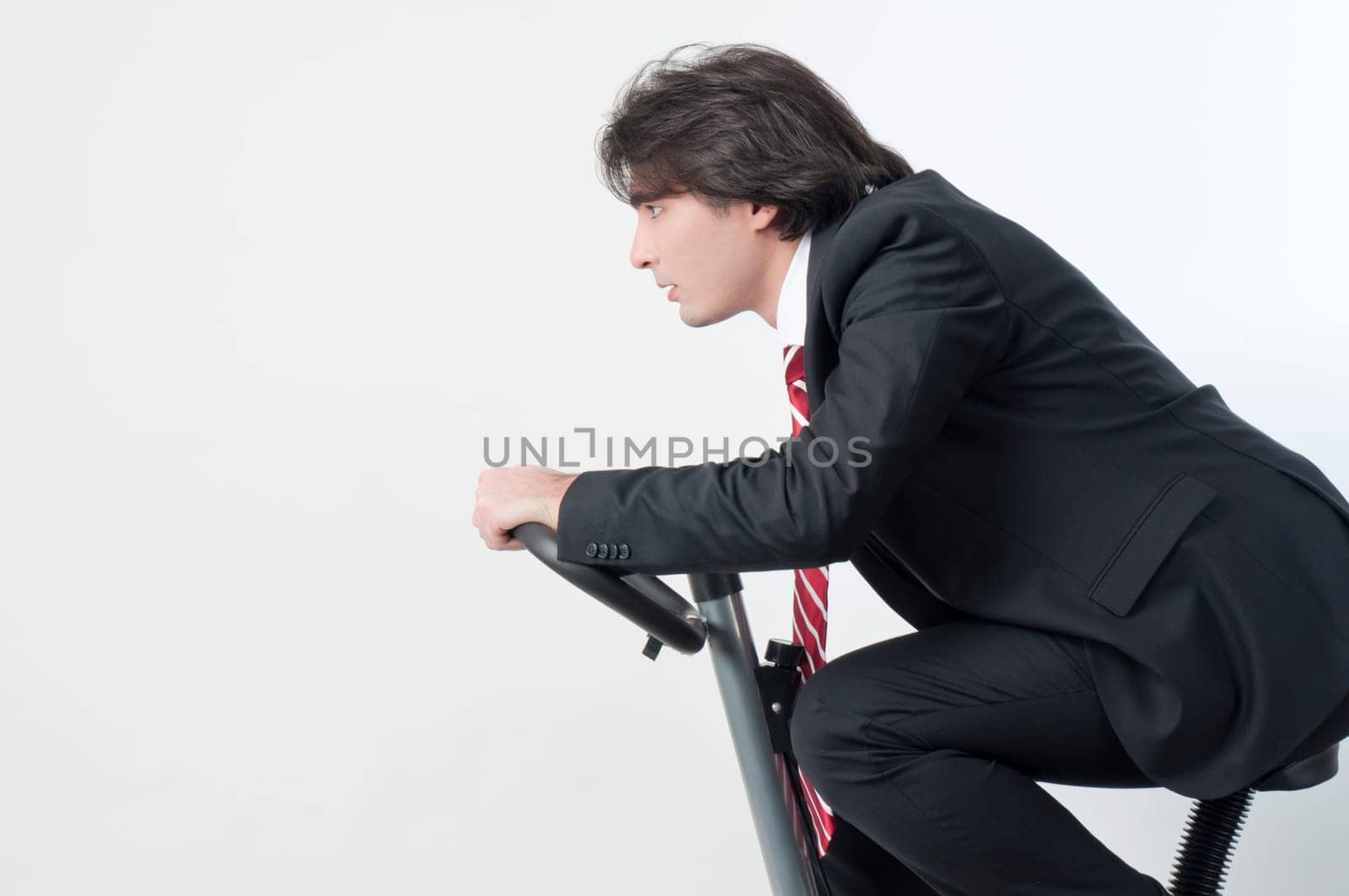 Young businessman riding a fitness bicycle isolated on white background