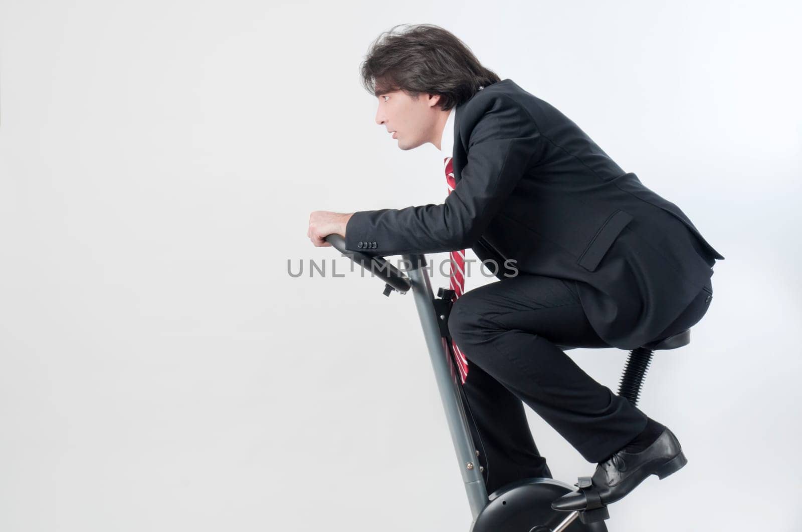 Young businessman riding a fitness bicycle isolated on white background