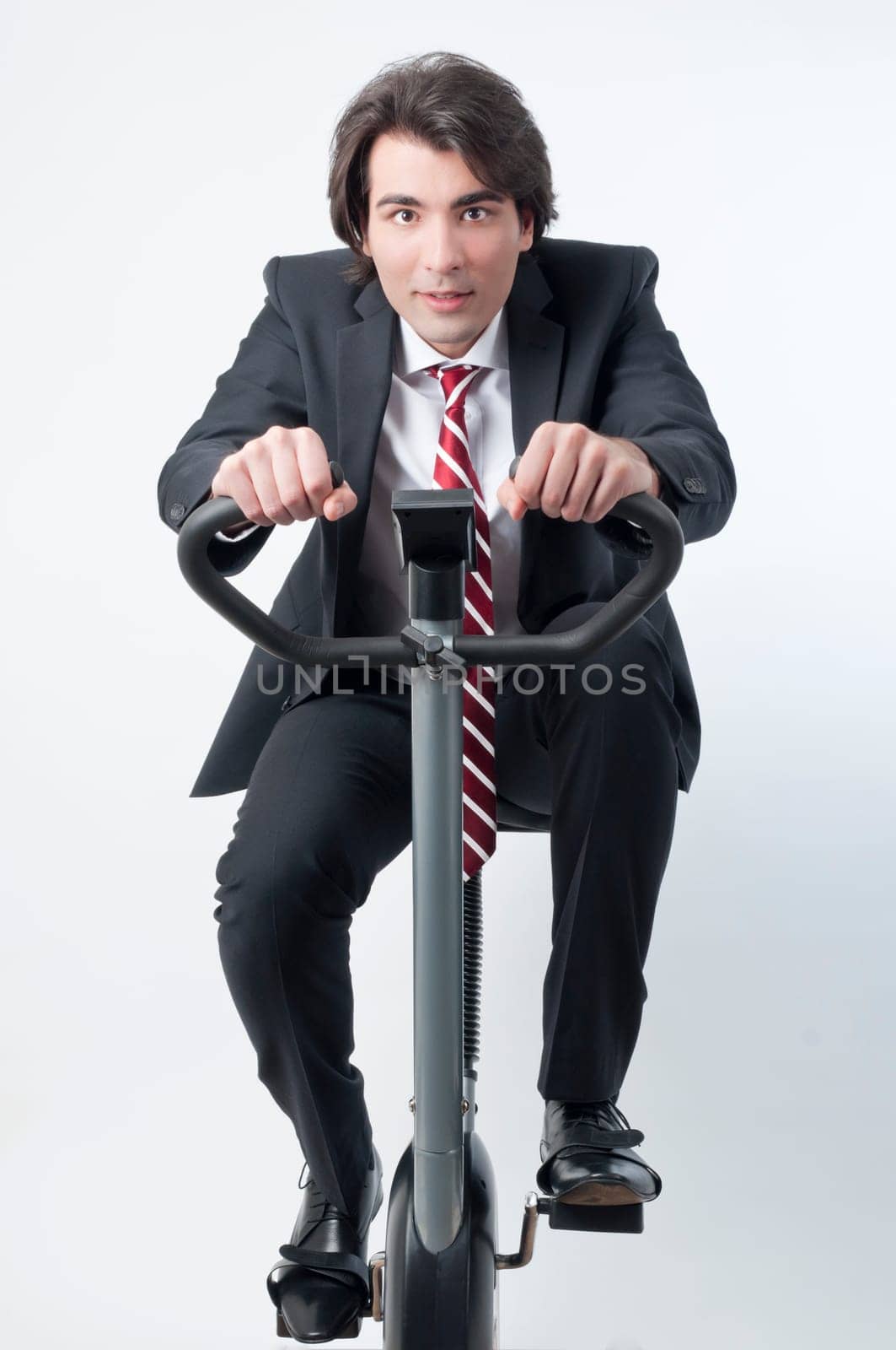 Young businessman riding a fitness bicycle isolated on white background