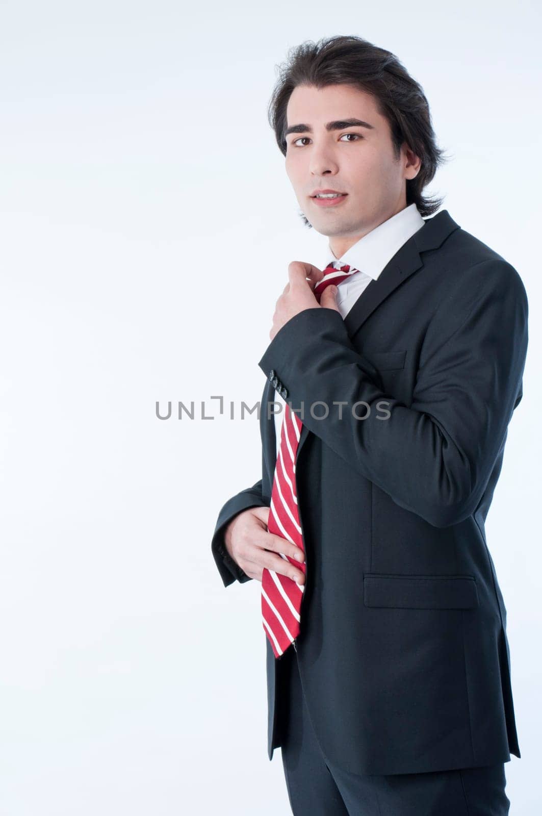 Confident young business man arranging his tie
