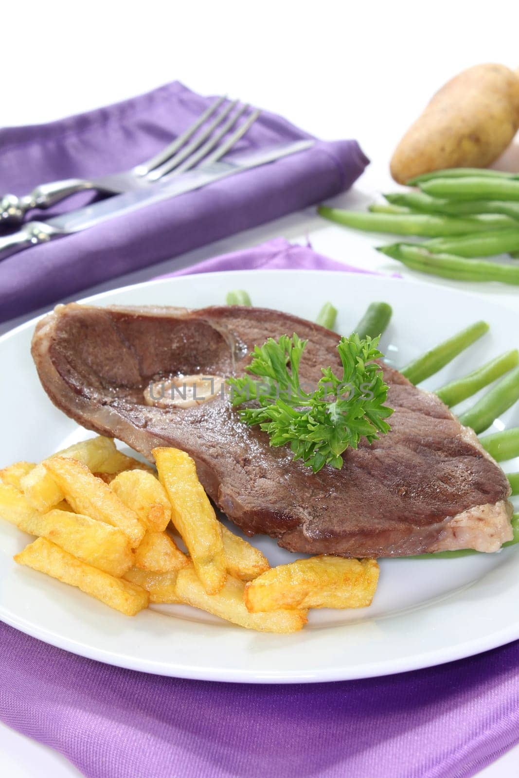 a slice of leg of lamb with green beans and fries