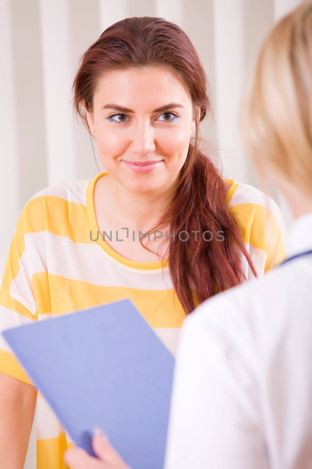 doctor with file talking with young female patient