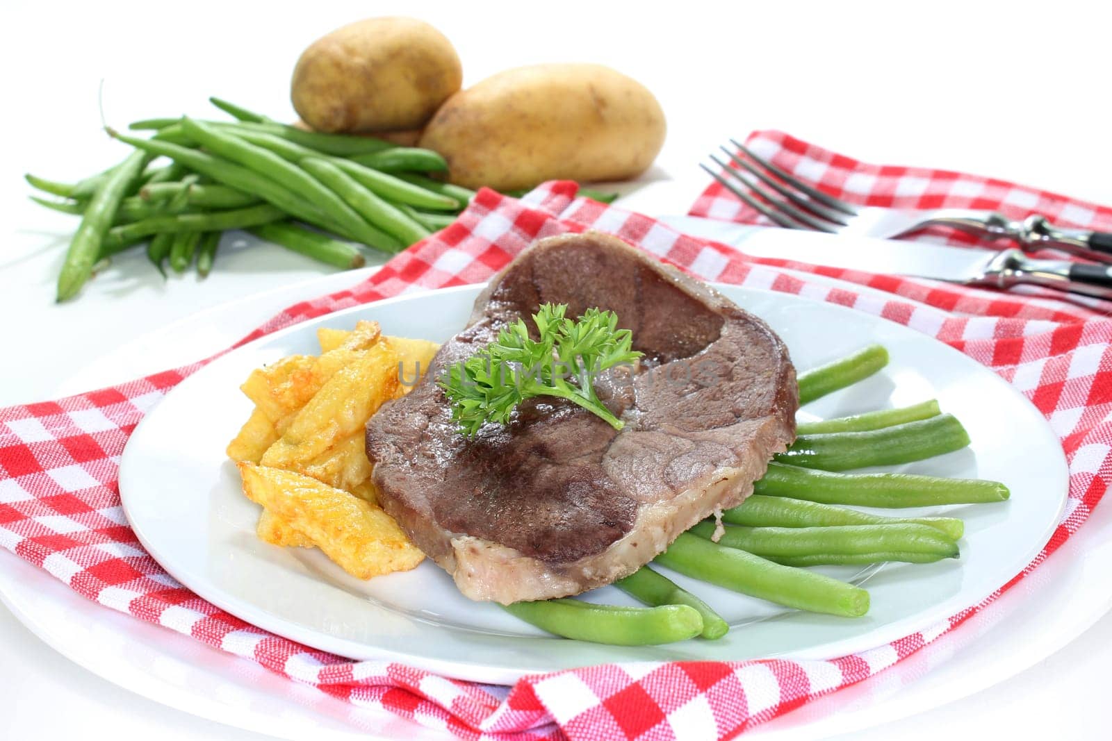 a slice of leg of lamb with green beans and fries
