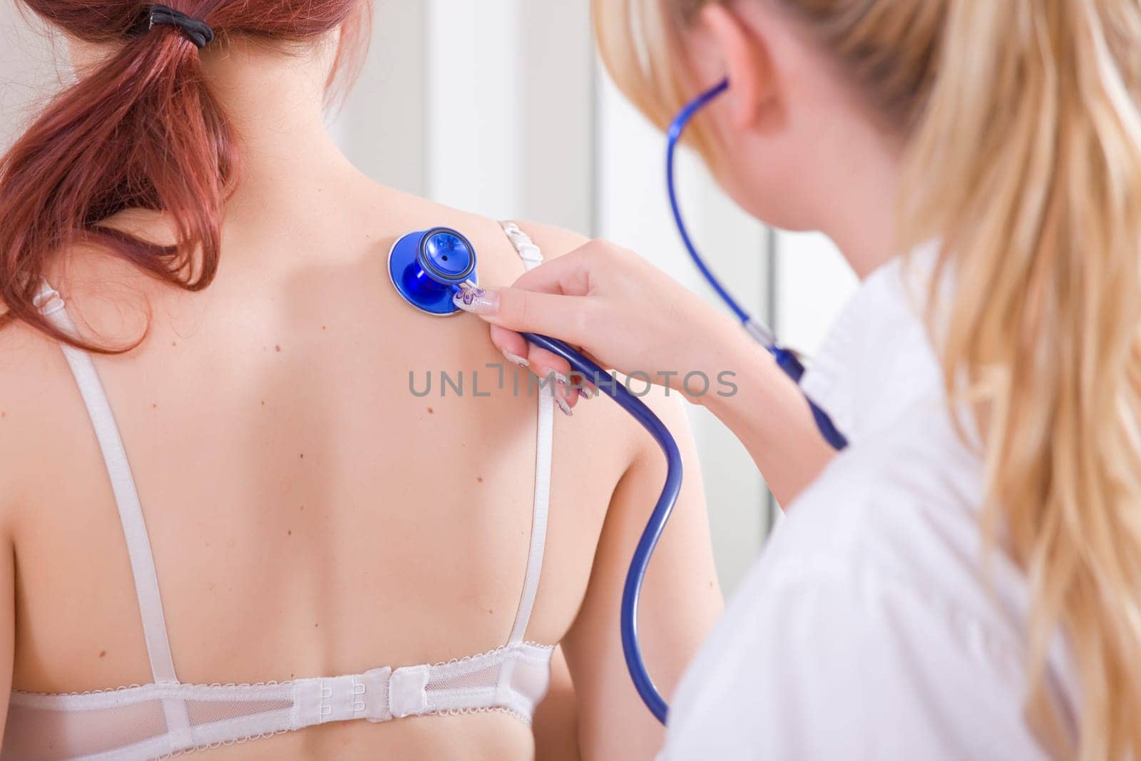 Female Doctor examine a young patient - lungs exam.