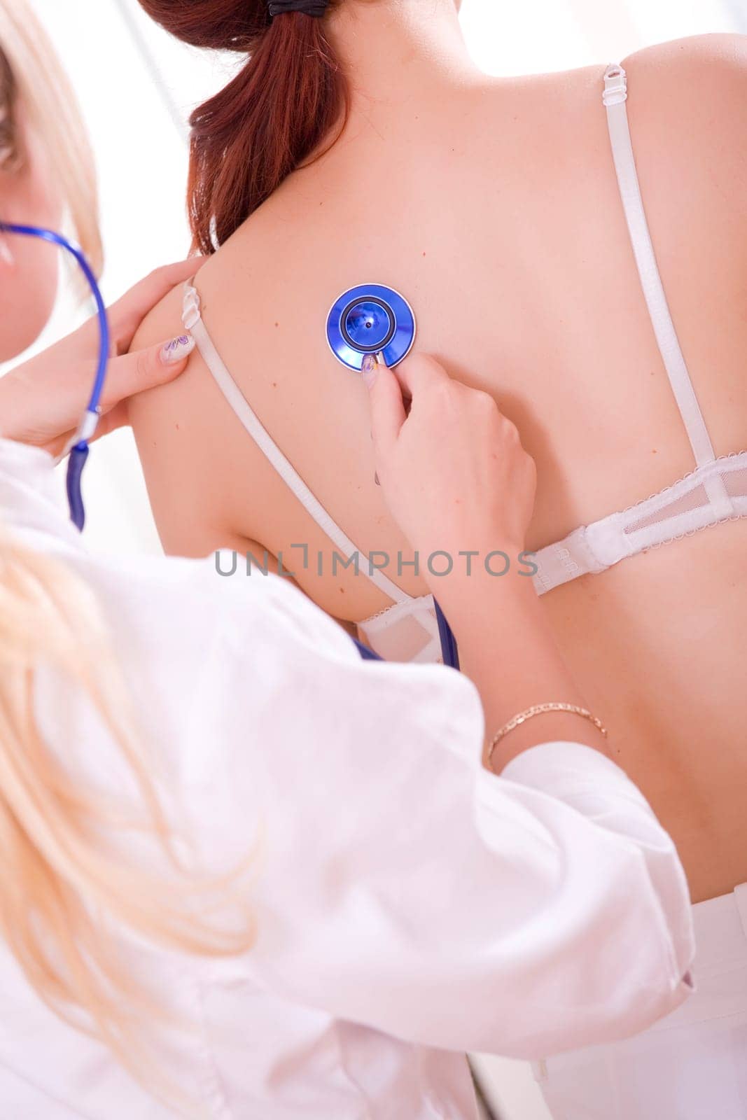 doctor with stethoscope examining young female patient