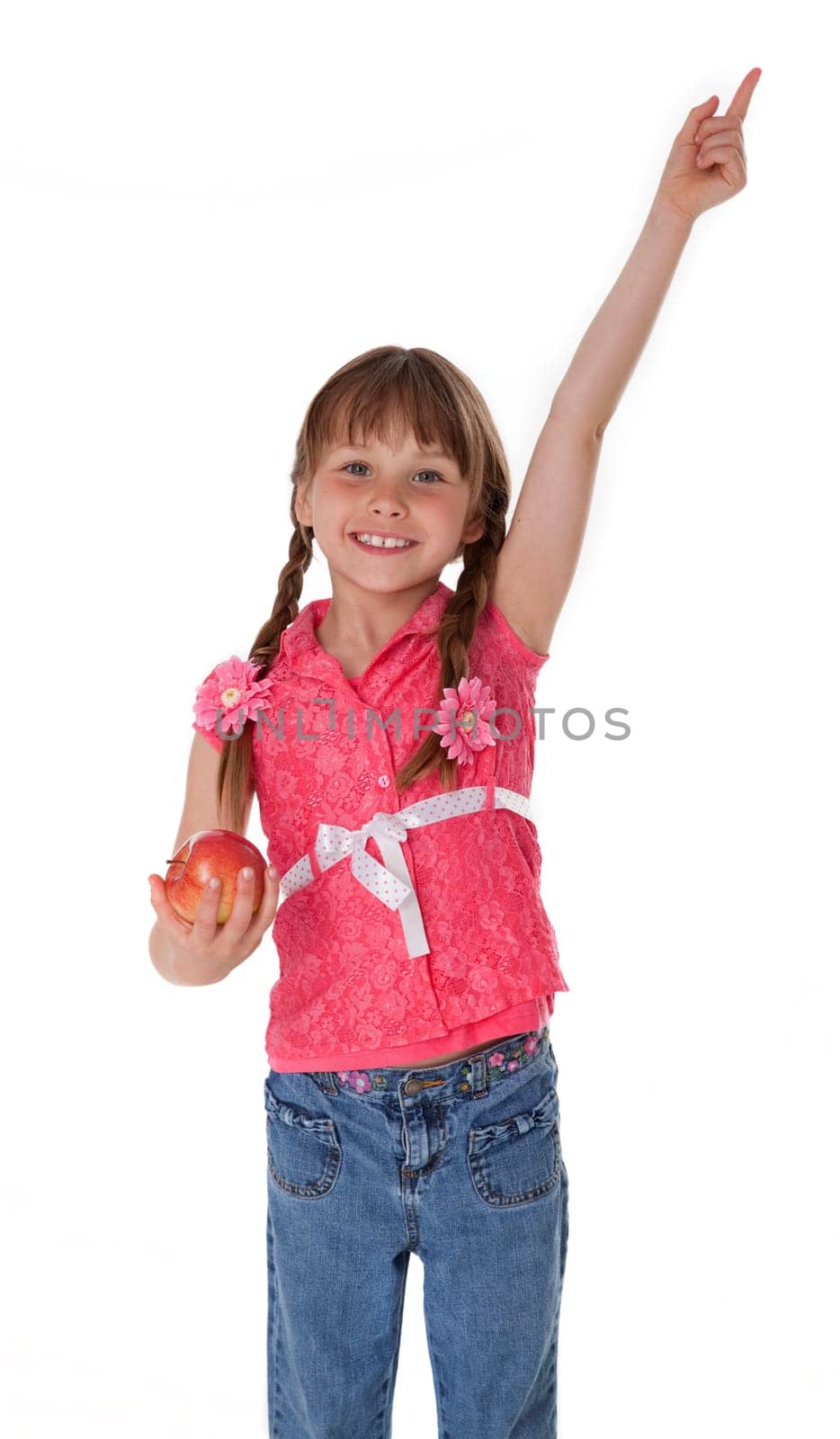 Studio photo of female child holding apple and pointing upward on white background.