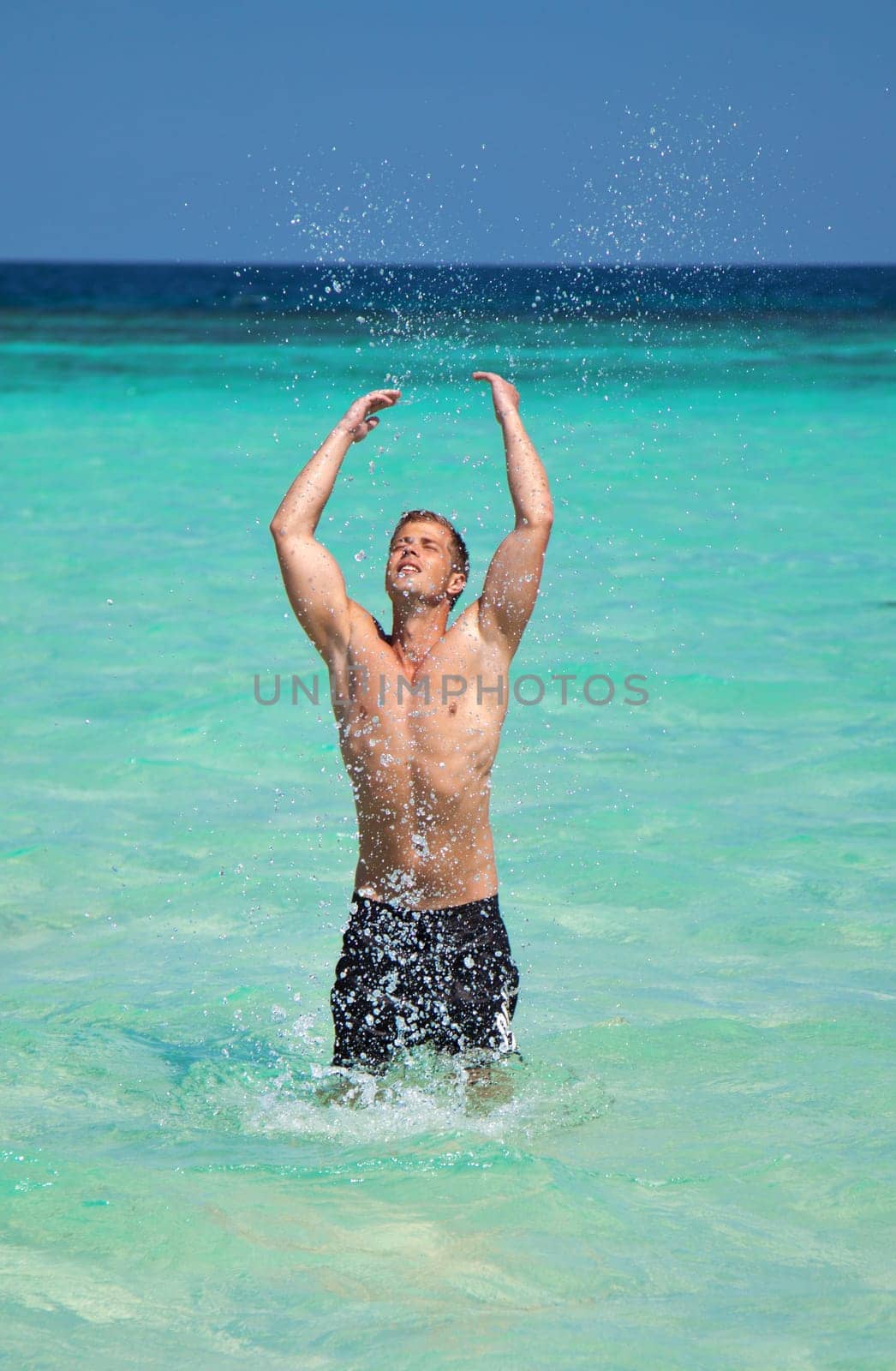 Young muscular man on turquoise beach