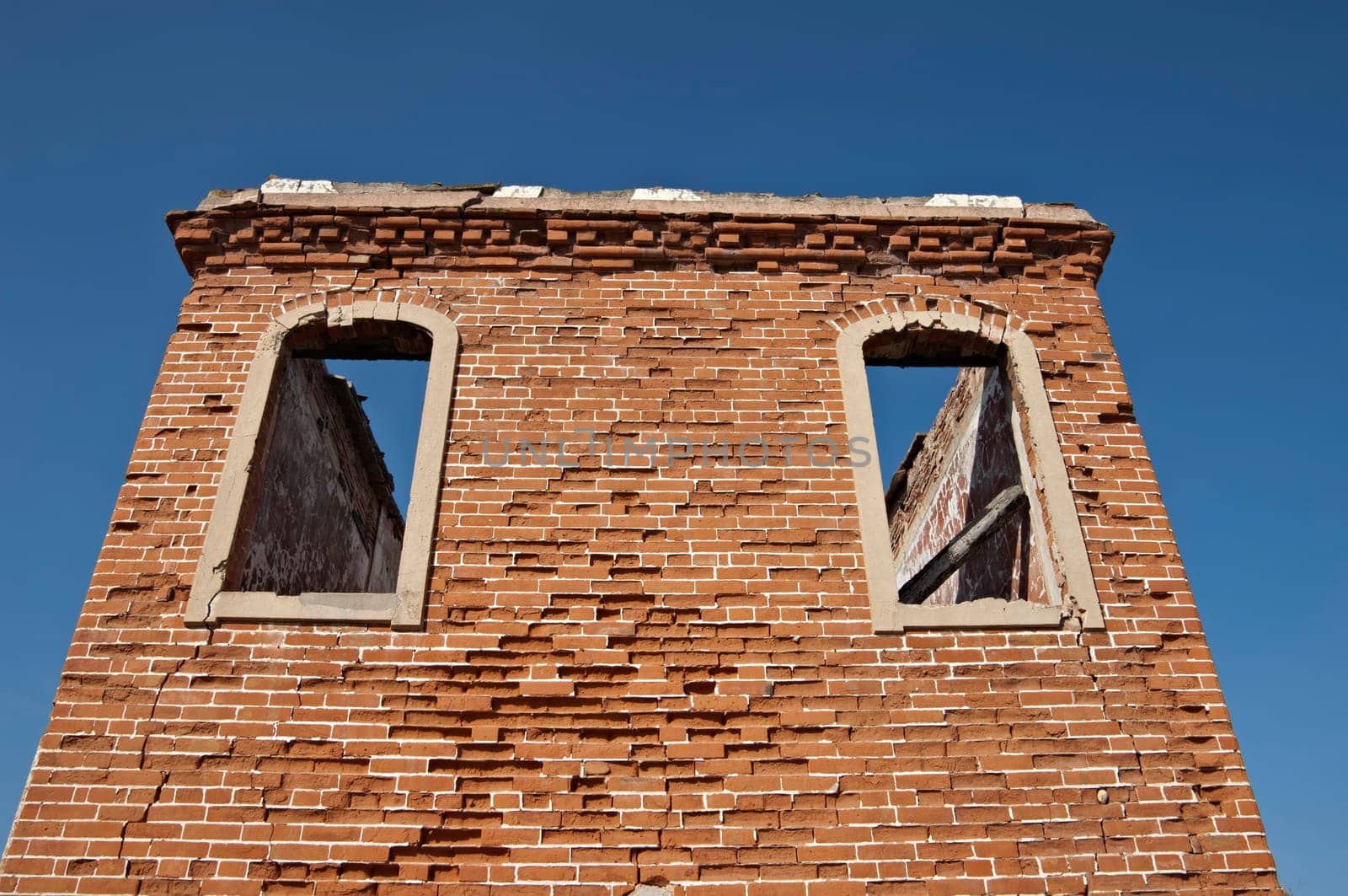 Ruins of a tower with brick walls against a blue clear sky