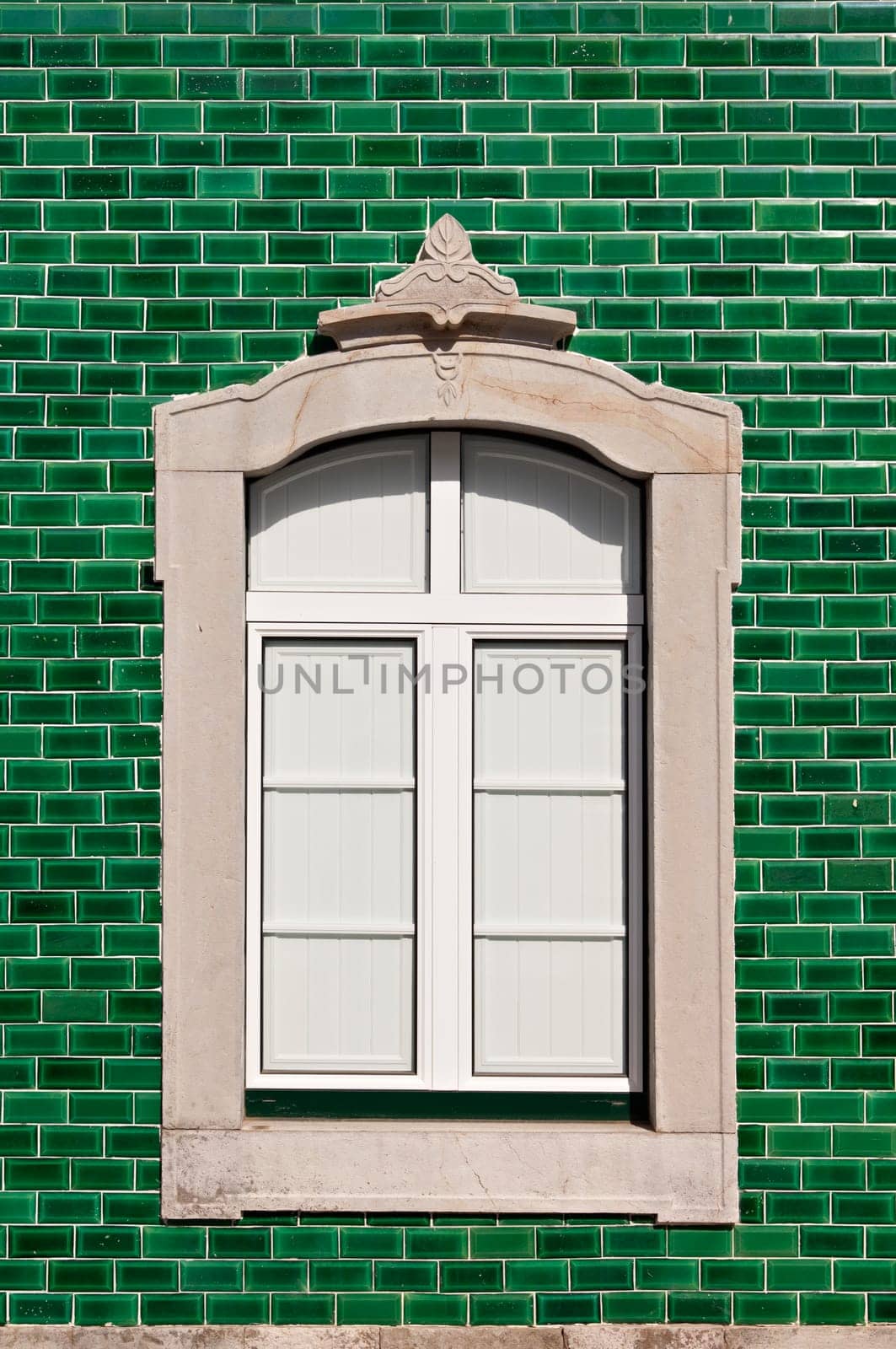 Traditional stone decorated window in a green tile background, Algarve, Portugal