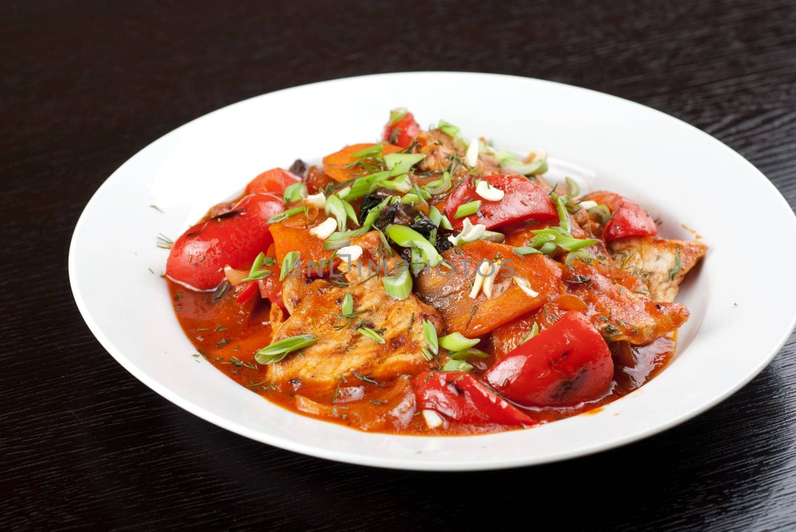 pork meat with tomato, pepper, prunes, garlic and green onion