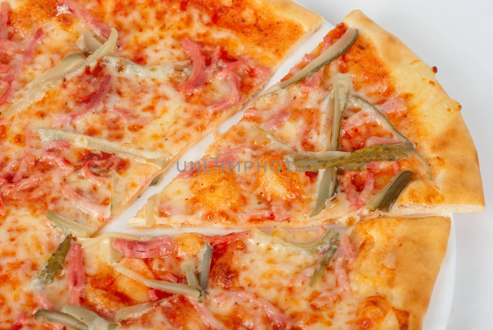 pizza closeup with boiled sausage, ham, marinated gherkin and mozzarella cheese
