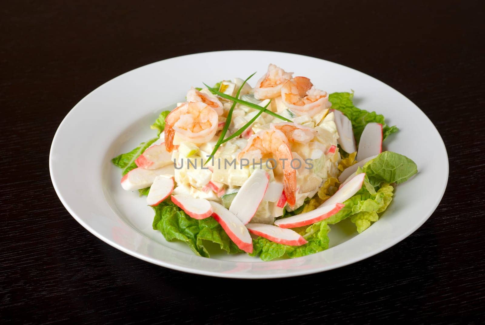 Salad of shrimps, crab meat, cucumbers, apples, potatoes, lettuce, maize, eggs and mayonnaise