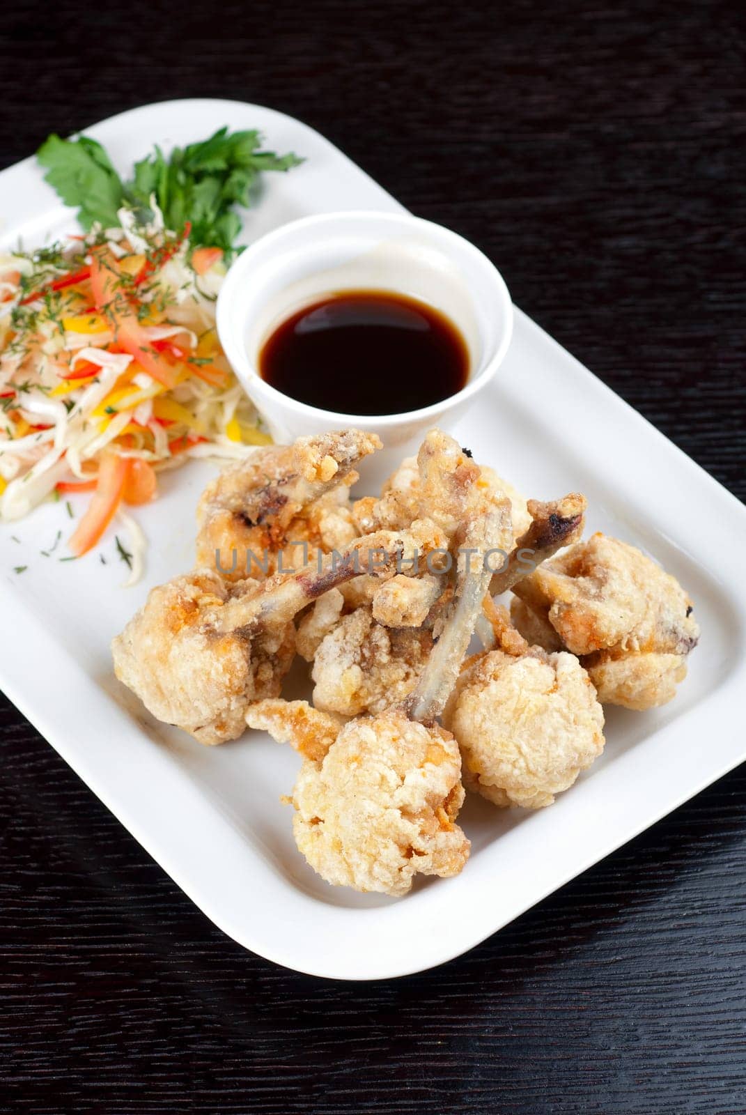 Fried chicken wings garnished with fresh vegetables with Teriyaki sauce