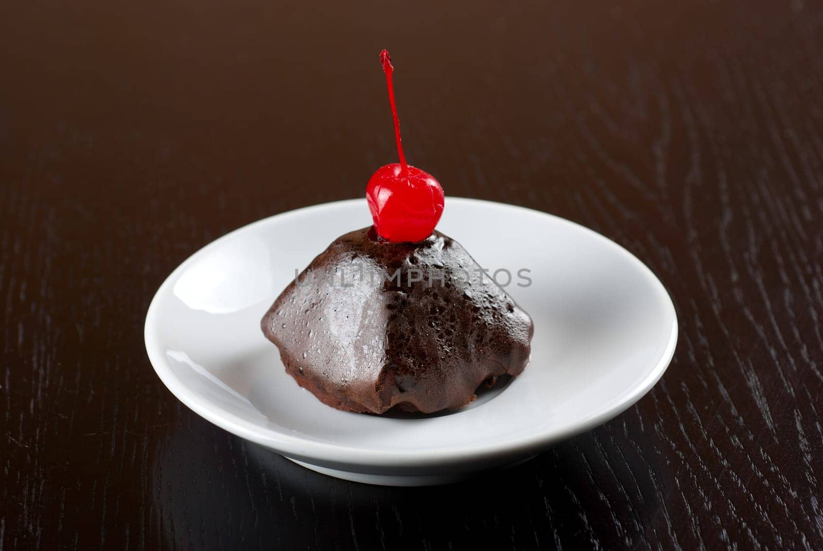 fresh baked chocolate cupcake with cherry on a wooden table