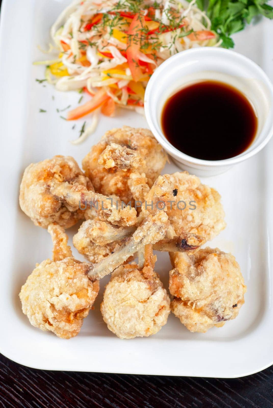 Fried chicken wings garnished with fresh vegetables with Teriyaki sauce
