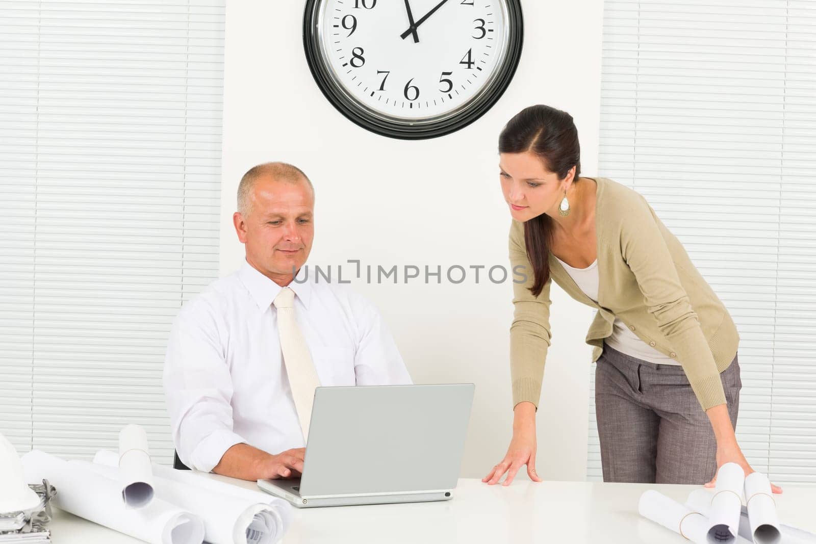 Professional architect people behind office table blueprints type on laptop