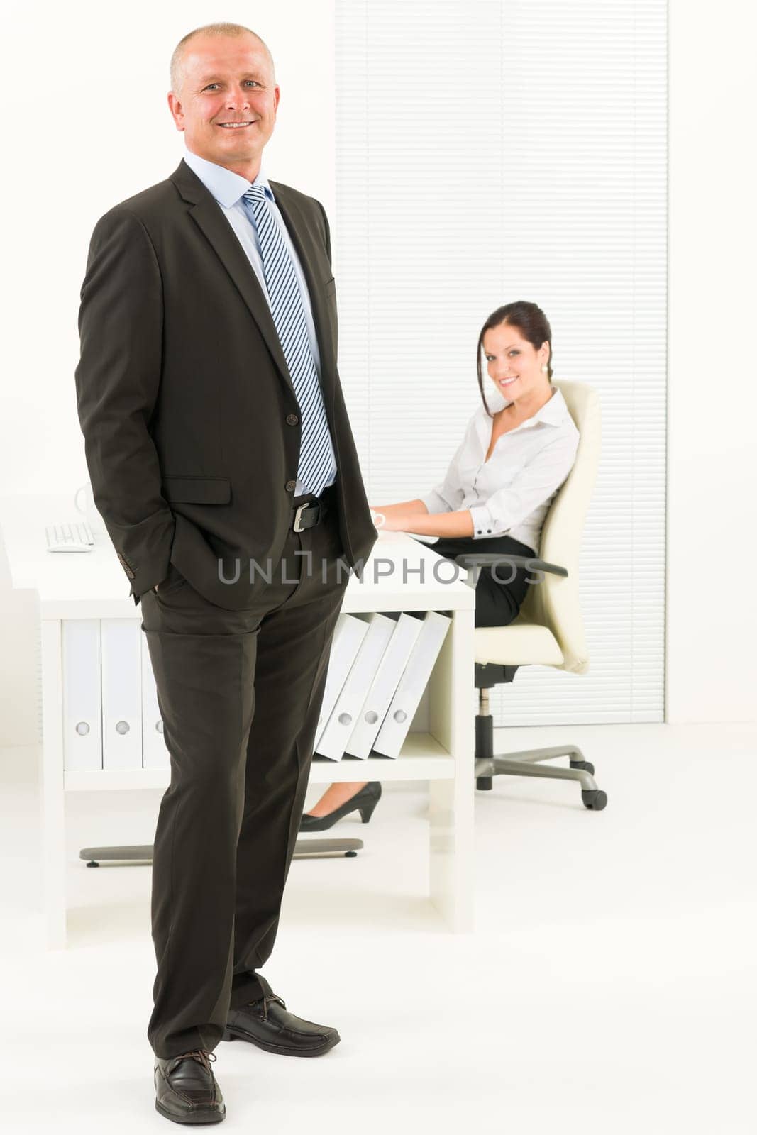 Professional senior mature businessman standing in office with attractive secretary