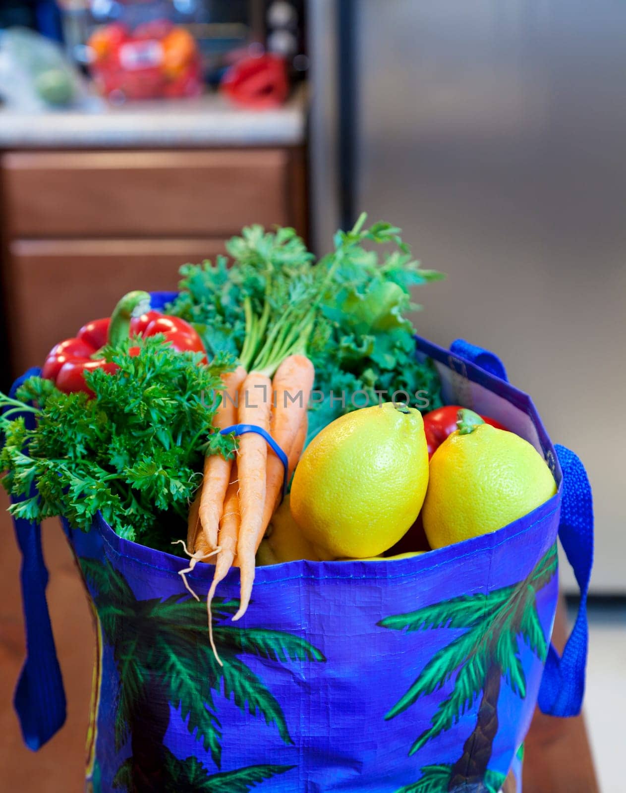 Fresh vegetable, fruits, and herbs in a grocery bag in the kitchen