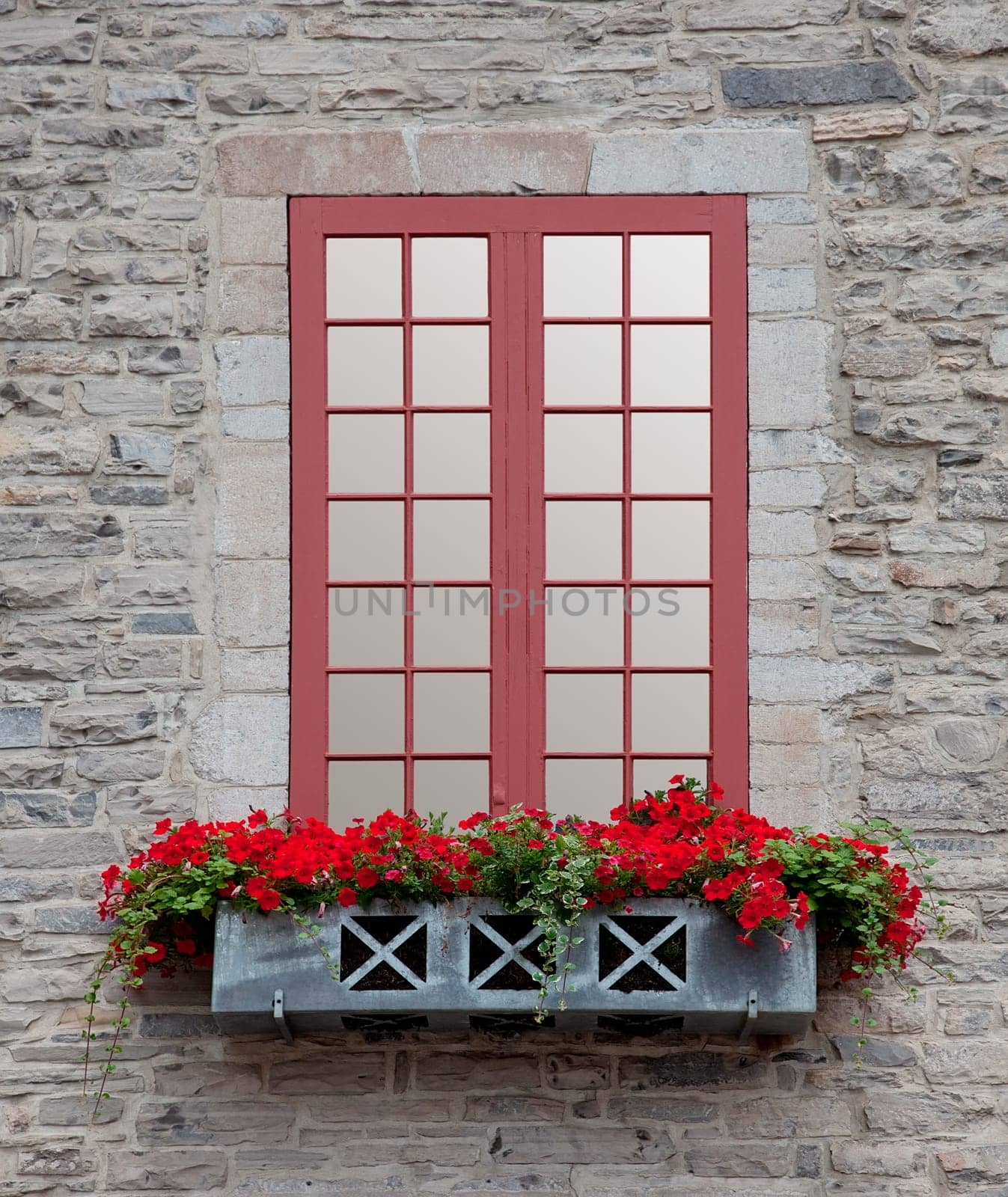 Front view of an old window and a flowerbox on an old stone building.