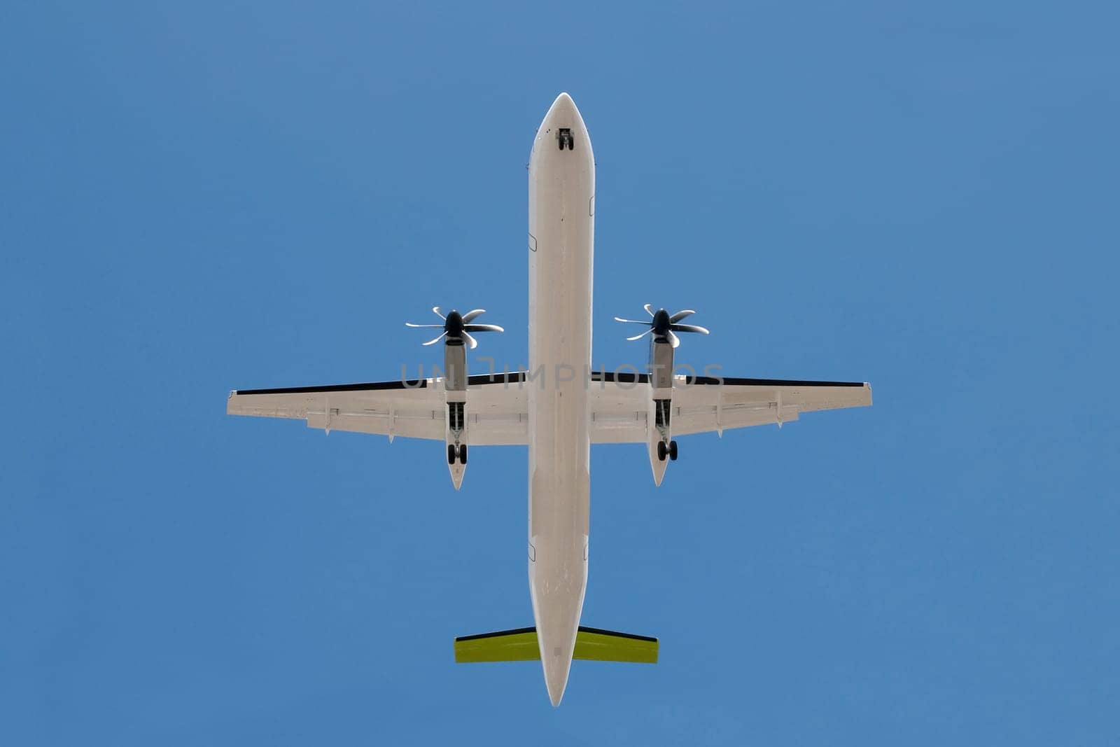 unmarked propeller aircraft overhead with landing gear down