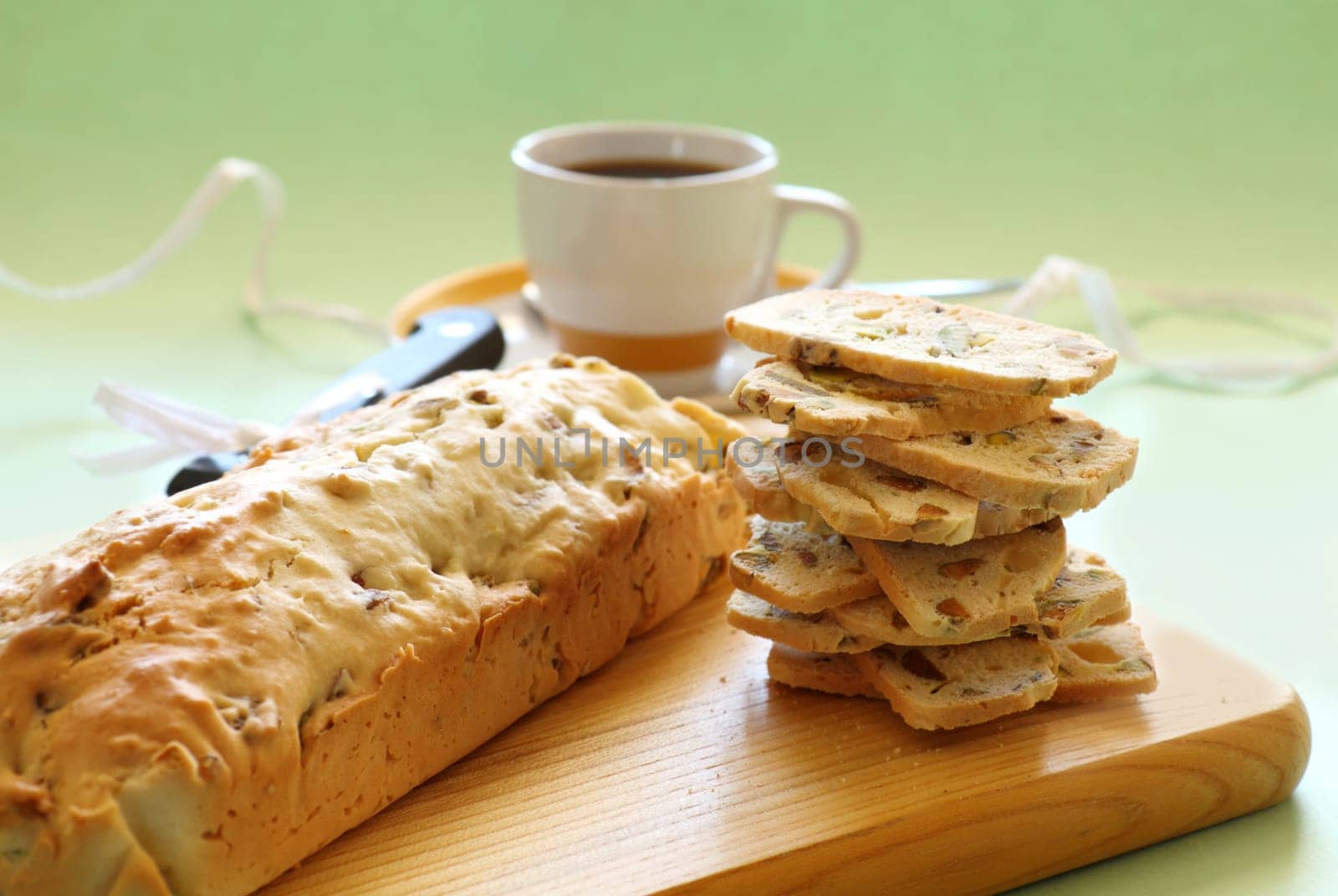 Fresh baked sweet pistachio bread sliced on a bread board with coffee.